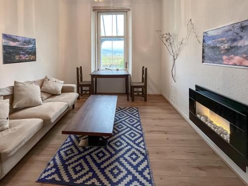 a living room with a couch and a fireplace at Lochside Hermitage in Rashfield