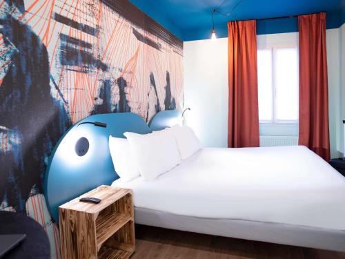 1 dormitorio con 1 cama blanca y un mural en Ibis Styles Paris Batignolles, en París