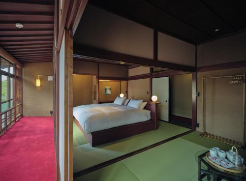 a bedroom with a large bed and a balcony at Komado ベンガラ in Komatsu