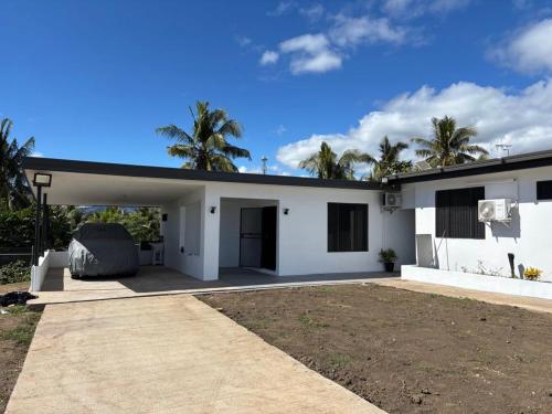 a white house with palm trees in the background at Lovu Villa in Lautoka