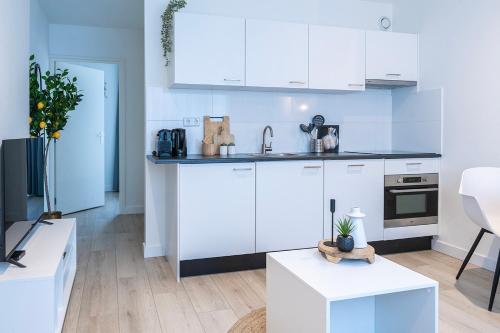Una cocina blanca con gabinetes blancos y una mesa. en Fresh And Equipped Apartment Near Hotspots, en Eindhoven
