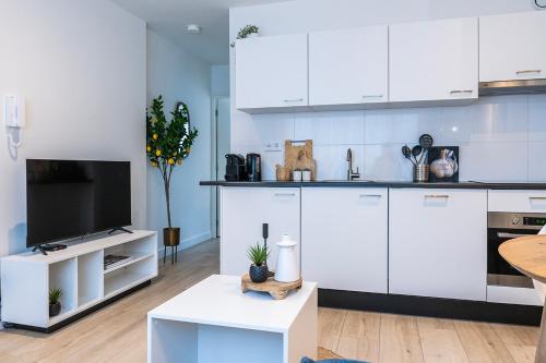 a kitchen with white cabinets and a flat screen tv at Fully Equipped Apartment, lovely bed in Eindhoven