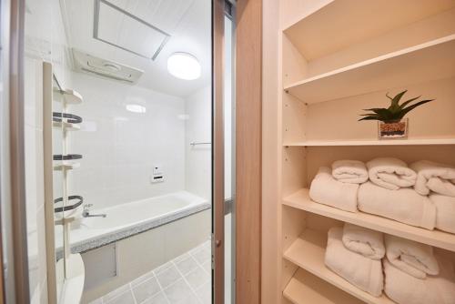 een badkamer met handdoeken, een wastafel en een bad bij ホワイトヒルズ in Tomigusuku