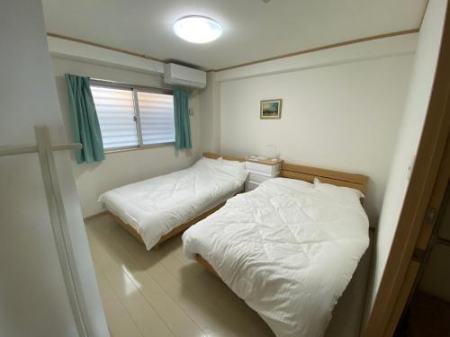 een slaapkamer met twee bedden en een raam bij ホワイトヒルズ in Tomigusuku
