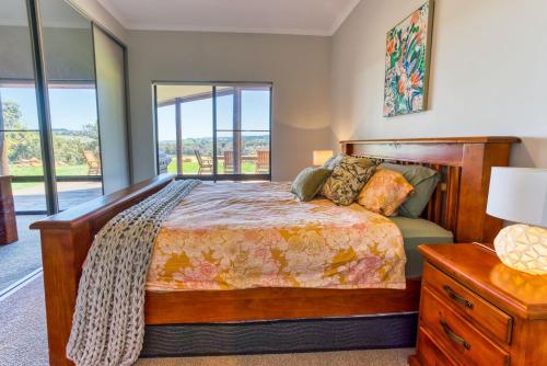 ナナップにあるNannup Rise Holiday Homeのベッドと大きな窓のある寝室