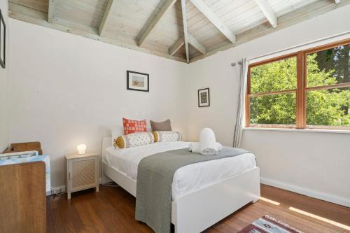 Una habitación blanca con una cama y una ventana en The Mud Brick House, en Leura