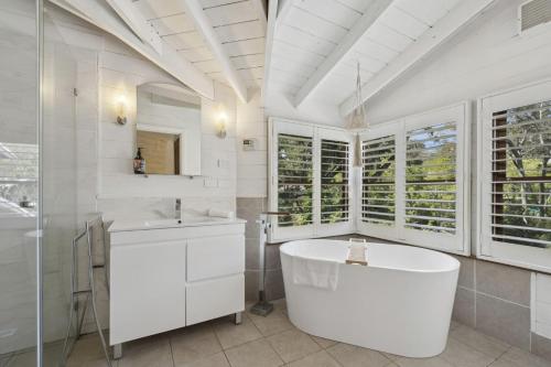 Un baño blanco con bañera y lavabo. en The Mud Brick House, en Leura