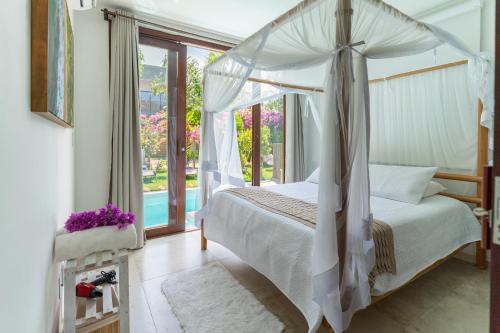 a bedroom with a canopy bed and a window at Casa incrível e aconchegante em Barra Grande - BA, Ponta do Mutá, em condomínio com excelente localização à 5 minutos da PRAIA e dos melhores BEACH CLUBS, próximo ao charmoso centrinho de Barra Grande e comércios in Marau