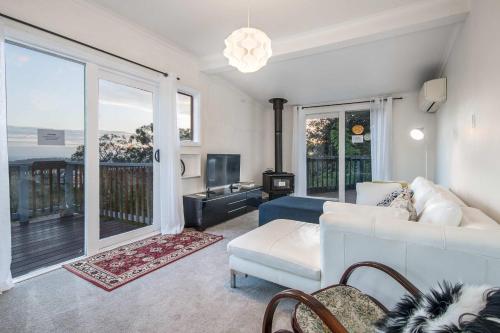 Una sala de estar con un sofá blanco y una ventana grande. en La Cachette in Upwey 3BR Retreat with Mountain Views, en Upwey