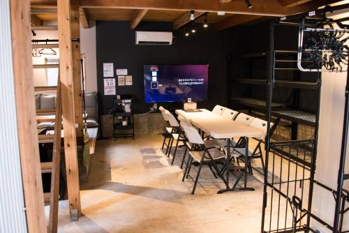 a dining room with a table and chairs and a tv at Rockstar Villa 江井浜STYLE in Awaji