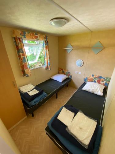 een kleine kamer met twee bedden en een raam bij CAMPING de la BUGE in Rochefort-Montagne
