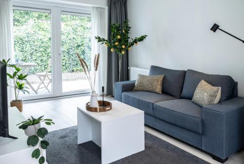 a living room with a blue couch and a table at Private Design Apartment w Garden & Parking in Eindhoven
