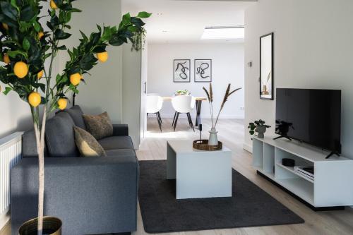 a living room with a grey couch and a tv at Private Design Apartment w Garden & Parking in Eindhoven
