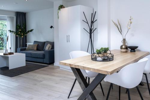 a dining room and living room with a wooden table and white chairs at Private Design Apartment w Garden & Parking in Eindhoven
