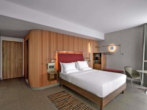 a hotel room with a large bed and a desk at Novotel Kinshasa La Gombe in Kinshasa