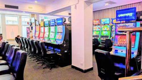 a row of slot machines in a room with chairs at Ambassadors Hotel in Adelaide