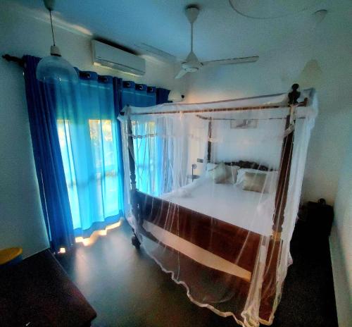 a bedroom with a canopy bed with blue curtains at Emerald Breeze villa in Galle