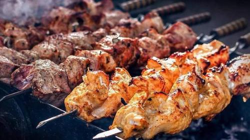 Un mucchio di carne su una griglia con le pinze di Aristocrat Resort Purbachal a Pānjora