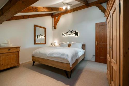 a bedroom with a bed with white sheets and a wooden door at Haus Gerlinde in Drachselsried