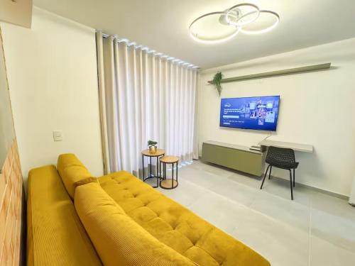 a large yellow couch in a living room with a tv at Confort total 2 Habitaciones, AC y excelente ubicación in Floridablanca