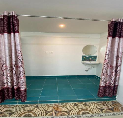 a bathroom with a toilet and a sink and curtains at kavieya residency in Pūrnānkuppam