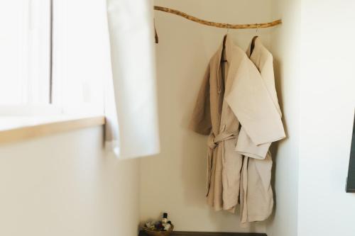a rack of clothes hanging on a wall next to a window at Matar baYaar מטר ביער in El-Rom