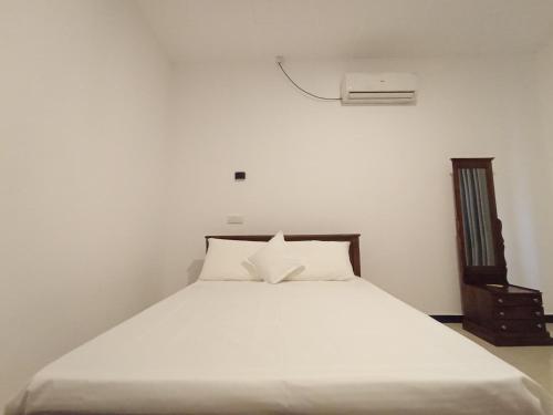 a bedroom with a white bed and a air conditioner at Villa Piore in Mirissa