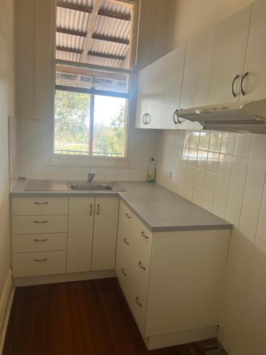 a kitchen with white cabinets and a sink and a window at Commercial Hotel Dowerin in Dowerin