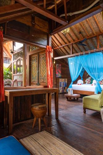 a room with a bed and a table and a couch at Bali Bohemia Huts in Ubud