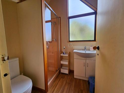 a small bathroom with a sink and a window at Tatahiti Haven - Sea Views & Classic Kiwi Charm in Tata Beach