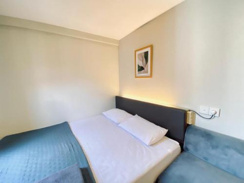 a small bedroom with a white bed and a blue couch at Andewi Cabin in Sempidi