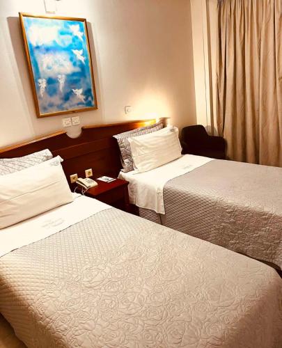 a hotel room with two beds and a window at Triton Hotel Piraeus in Piraeus