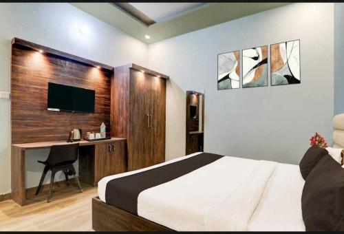 a bedroom with a bed and a desk and a television at Hotel O Sultanpur Railway Junction Formerly Sanskar Marriage Lawan in Sultānpur