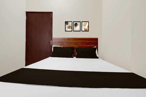 a bedroom with a white bed with a wooden headboard at Hotel O Sultanpur Railway Junction Formerly Sanskar Marriage Lawan in Sultānpur