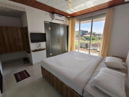 a bedroom with a large bed and a large window at Winter Cloud in Mahabaleshwar