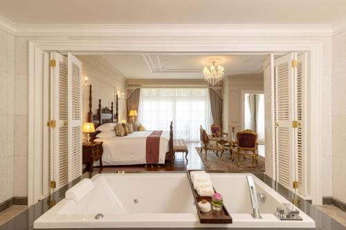 Ping Pura Riverside Resort & Spa Chiang Mai في شيانغ ماي: حمام كبير مع حوض استحمام وغرفة نوم
