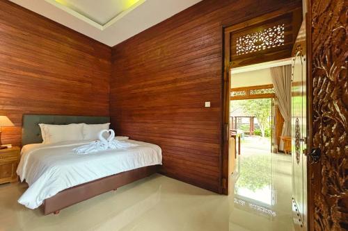 a bedroom with a bed and a wooden wall at Arisa Villa by AGATA in Menanga