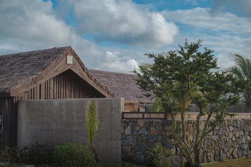 ein Haus mit einer Steinmauer und einem Baum in der Unterkunft Jeju Sentosa Hallim in Jeju-do