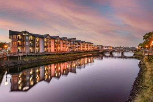 a row of apartment buildings by a river at night at Kathryn Riverfront Inn, an Ascend Collection Hotel in Seaside