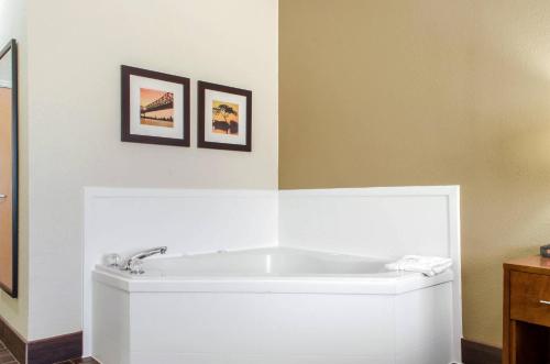a white tub in a bathroom with two pictures on the wall at Comfort Inn & Suites Covington - Mandeville in Covington