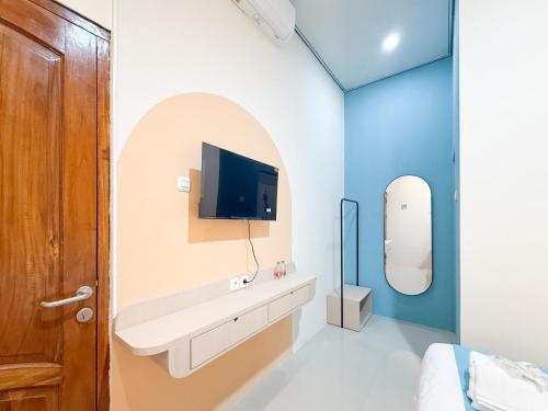 ein Badezimmer mit Waschbecken und einem Fernseher an der Wand in der Unterkunft Sans Stay Harmoni 88 Ambarukmo Plaza Yogyakarta in Adi Sutjipto