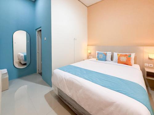 ein Schlafzimmer mit einem großen Bett und einem Spiegel in der Unterkunft Sans Stay Harmoni 88 Ambarukmo Plaza Yogyakarta in Adi Sutjipto
