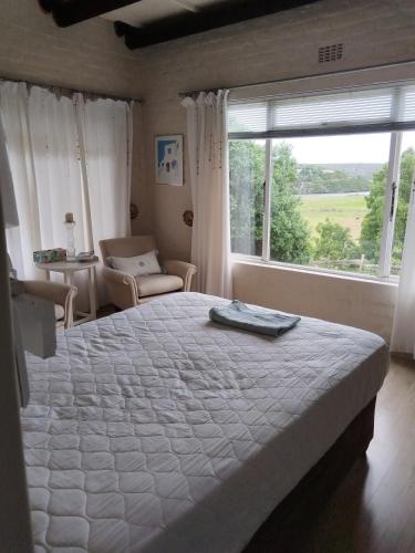 a bedroom with a large bed and a window at Rivers edge cottage in Stilbaai