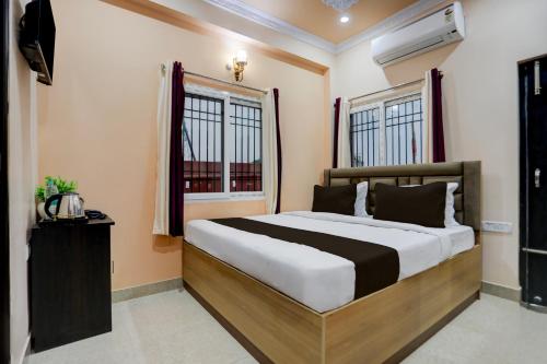 a bedroom with a large bed and two windows at Hotel O kumar inn in Lok Nayak Jayaprakash Airport