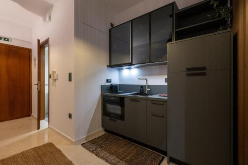 a kitchen with black cabinets and a sink and a stove at Urban Nest in Kalamata