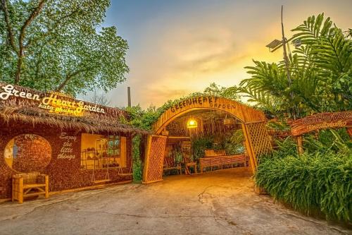 a building with an archway in a yard with trees at Greenheart Garden View Camp Phuket in Kata Beach