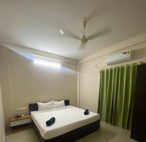 a bedroom with a white bed and a green curtain at NeuroGreen Serviced Apartments in Kottakkal