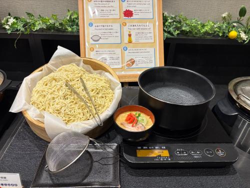una encimera con un tazón de fideos y dos ollas y sartenes en Nest Hotel Hakata Station, en Fukuoka