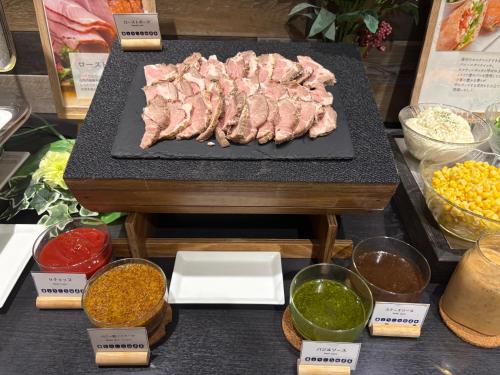 una mesa con una bandeja de carne y otros ingredientes en Nest Hotel Hakata Station, en Fukuoka