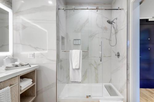 a white bathroom with a shower and a sink at Cambria Hotel Waco University Riverfront in Waco